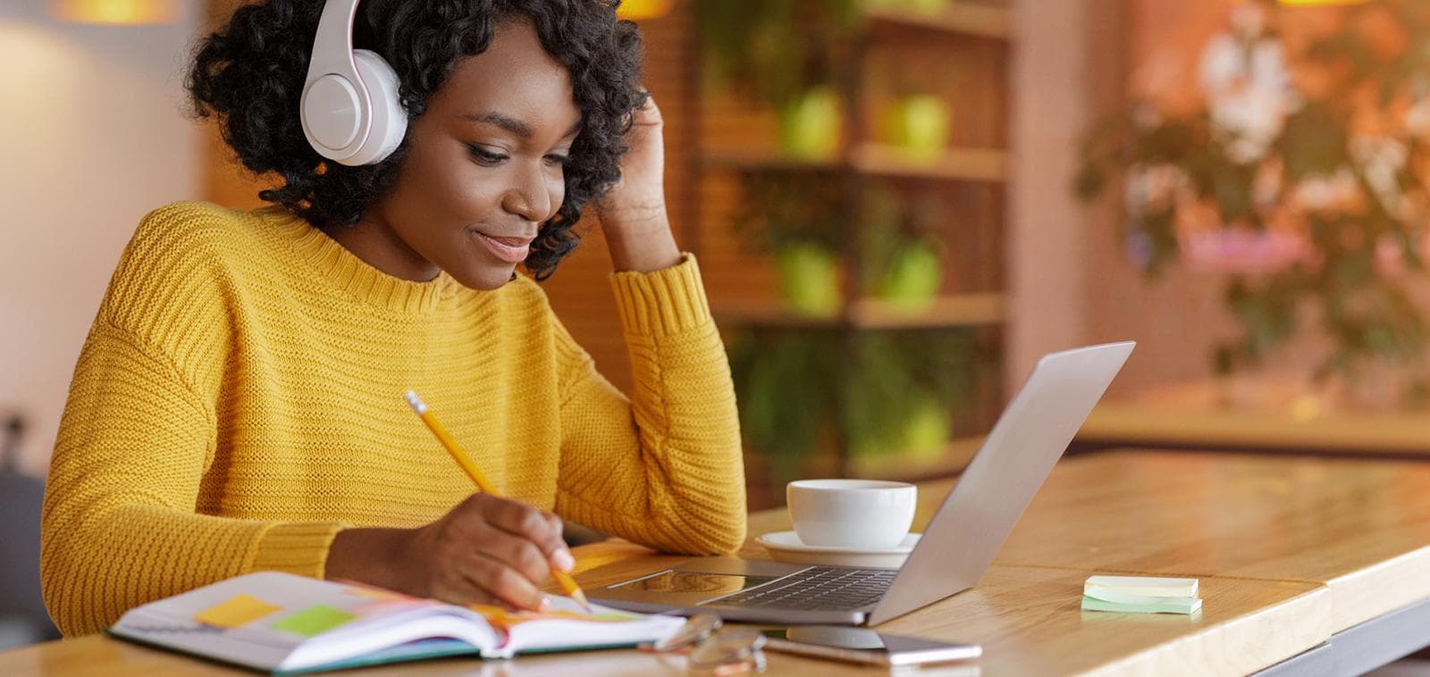 Student studying humanities subjects with laptop, books, and headphones in a focused learning environment